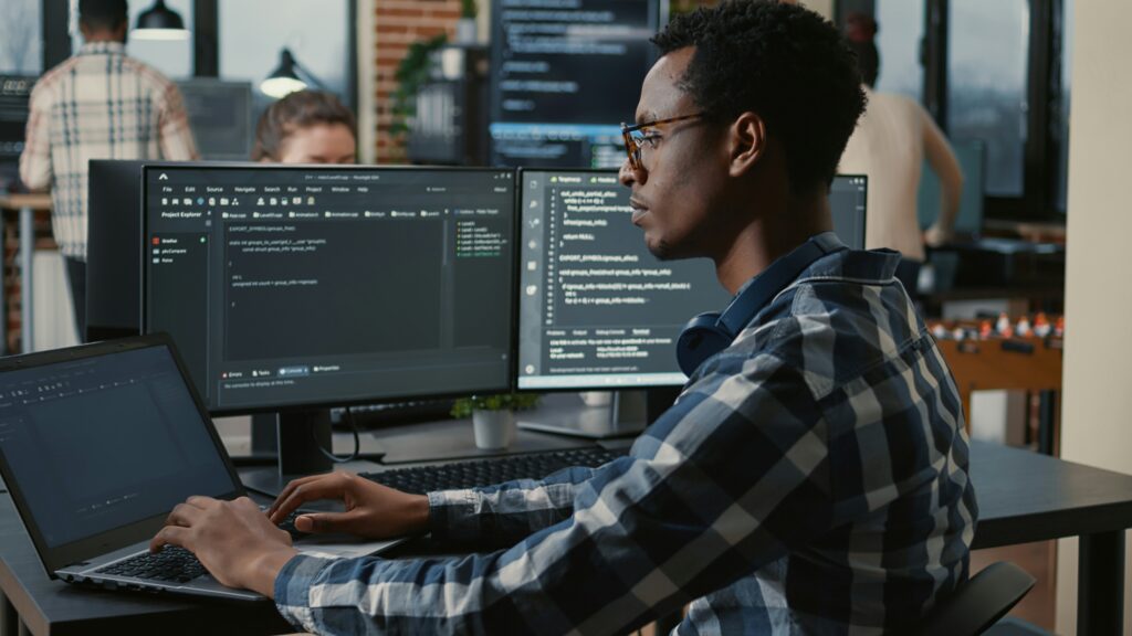 A professional software developer sitting at a computer, writing code and programming software