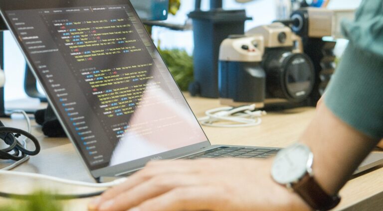 A person sitting at a computer, writing code for backend development, programming an app as an in-house developer.